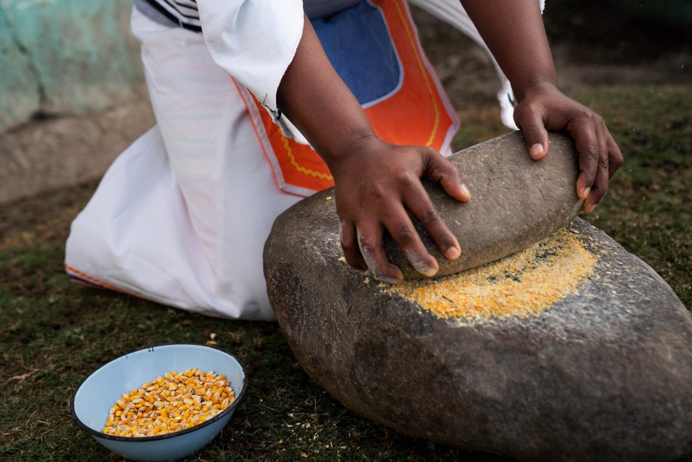 a person grinding corn on a rock