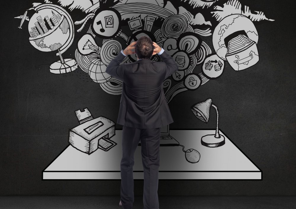 Man in a suit holding his head in front of a wall with chaotic illustrations of data and ideas, symbolizing information overload and the need to enhance cognitive function.